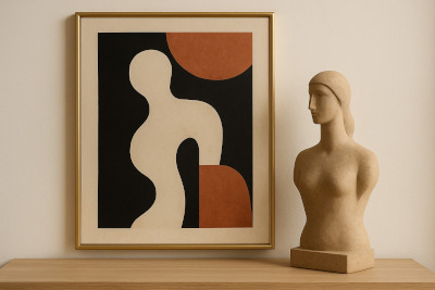 Quadro com arte abstrata em tons de preto, bege e terracota apoiado sobre um móvel de madeira clara, ao lado de um busto decorativo de cor bege.